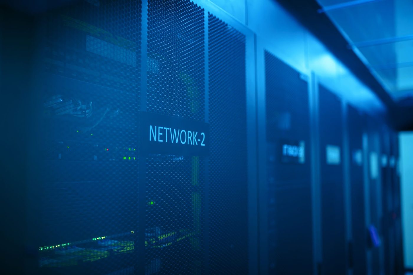 Corredor de racks em sala de servidores, com equipamentos de rede iluminados em azul.